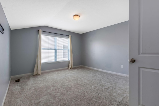 spare room with light carpet, baseboards, visible vents, and lofted ceiling