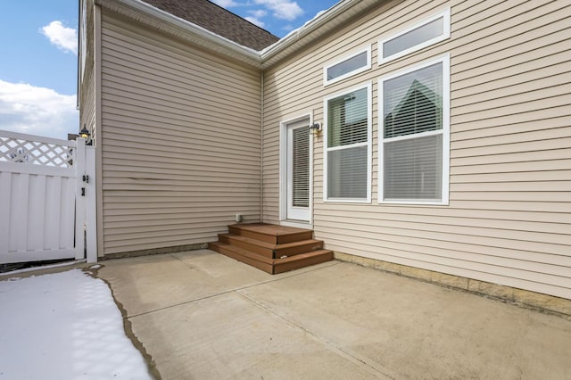 exterior space with a gate, a patio area, and roof with shingles