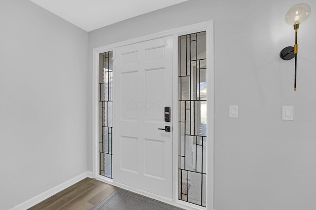 foyer entrance with dark wood-style floors, a healthy amount of sunlight, and baseboards