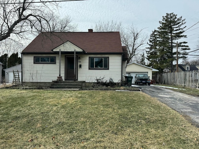 bungalow featuring an outbuilding, fence, roof with shingles, a front lawn, and a chimney