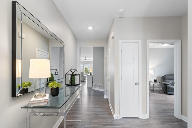 corridor with dark wood-style floors, visible vents, and baseboards