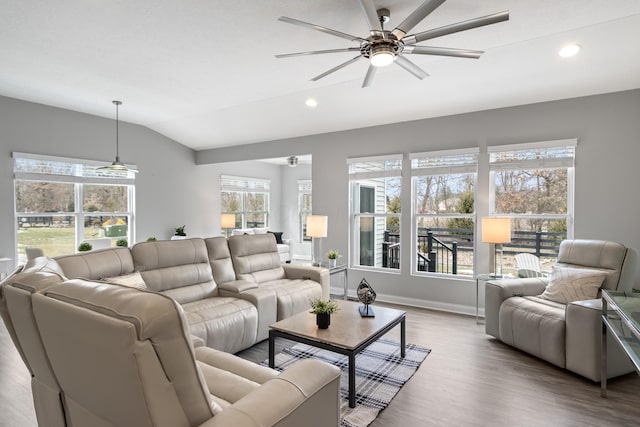 living area with a healthy amount of sunlight, vaulted ceiling, light wood finished floors, and ceiling fan