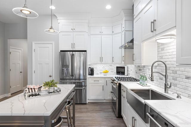 kitchen with decorative backsplash, light stone counters, decorative light fixtures, stainless steel appliances, and white cabinetry