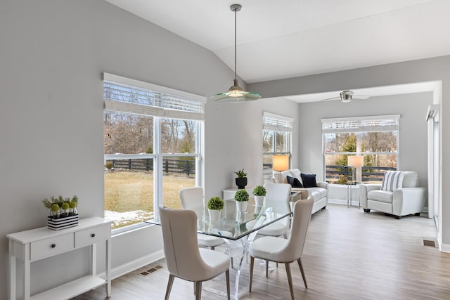 dining space featuring vaulted ceiling, wood finished floors, visible vents, and baseboards