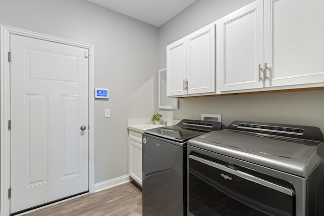 washroom featuring cabinet space, a sink, light wood-type flooring, independent washer and dryer, and baseboards