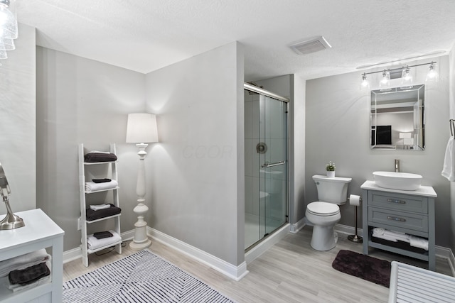 full bath with toilet, wood finished floors, vanity, visible vents, and a stall shower