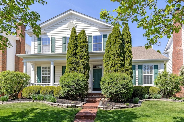 traditional-style house featuring a front yard and covered porch
