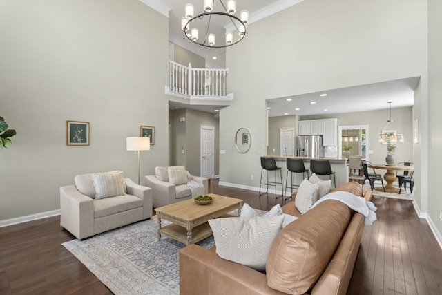 living room featuring a chandelier, crown molding, baseboards, a towering ceiling, and dark wood finished floors