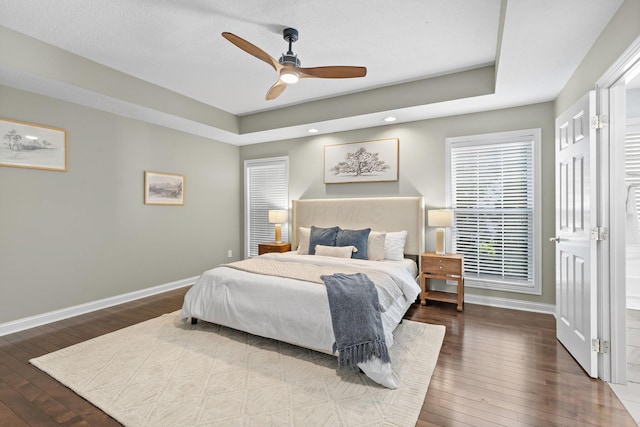 bedroom with recessed lighting, ceiling fan, a raised ceiling, baseboards, and hardwood / wood-style flooring