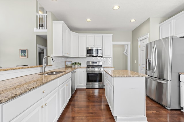 kitchen featuring light stone countertops, a sink, stainless steel appliances, tasteful backsplash, and white cabinets