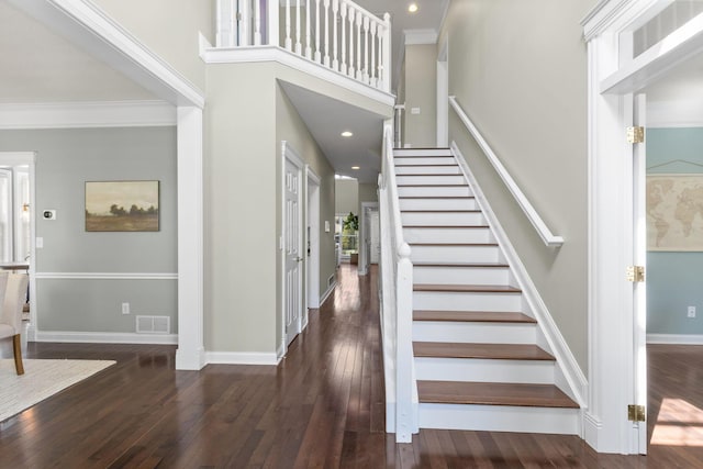 entryway featuring hardwood / wood-style flooring, visible vents, baseboards, ornamental molding, and stairs