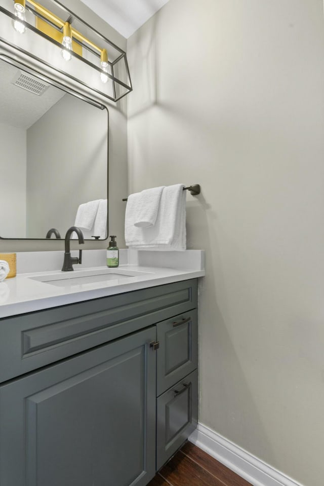 bathroom with baseboards, visible vents, wood finished floors, and vanity