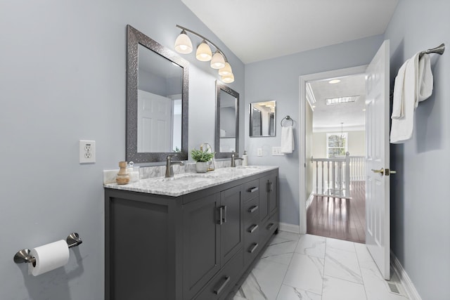 bathroom with baseboards, marble finish floor, double vanity, and a sink