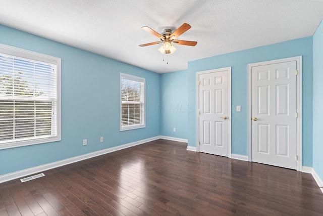 unfurnished bedroom with a ceiling fan, visible vents, wood finished floors, and baseboards