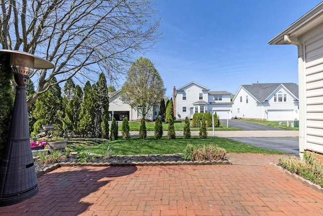 exterior space featuring a residential view, driveway, a yard, and a garage