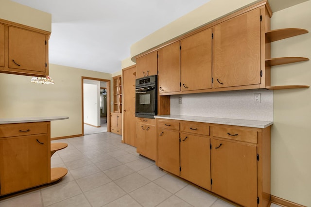 kitchen featuring baseboards, brown cabinets, light countertops, open shelves, and black oven