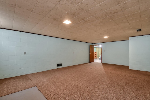 empty room featuring concrete block wall and visible vents