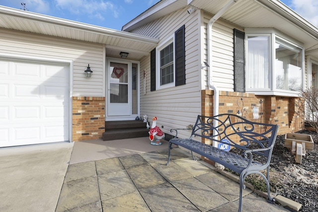 view of exterior entry with a garage and brick siding