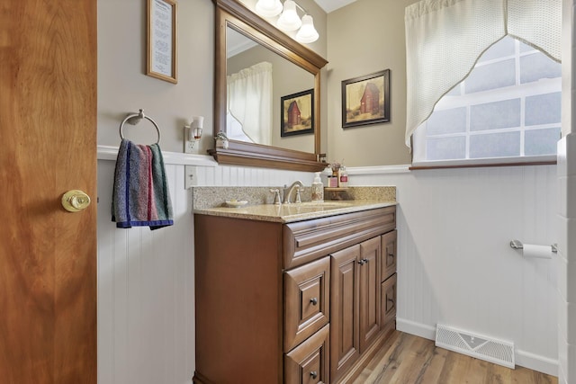 bathroom featuring a wainscoted wall, wood finished floors, vanity, and visible vents