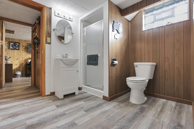 full bath with a shower stall, wooden walls, wood finished floors, and vanity