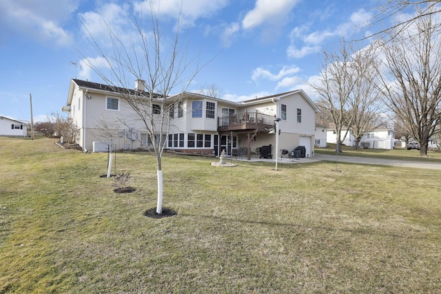 back of house featuring a chimney, a yard, a wooden deck, and an attached garage