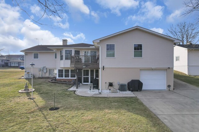 rear view of property featuring concrete driveway, a patio, a chimney, an attached garage, and a yard