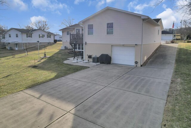 back of property featuring an attached garage, a balcony, central air condition unit, a yard, and stucco siding