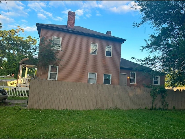 view of home's exterior with a yard, fence, and a chimney