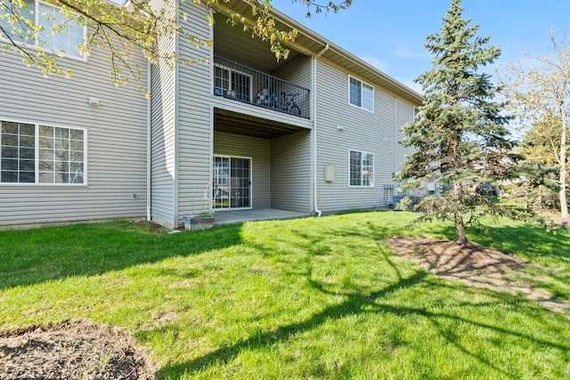 rear view of property with a patio, a yard, and a balcony