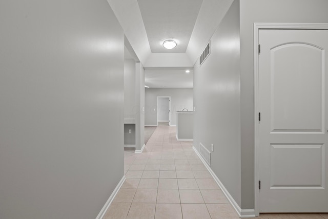 hall featuring light tile patterned flooring, visible vents, and baseboards