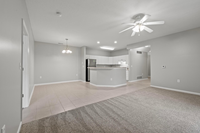 unfurnished living room featuring baseboards, light tile patterned flooring, visible vents, and ceiling fan with notable chandelier
