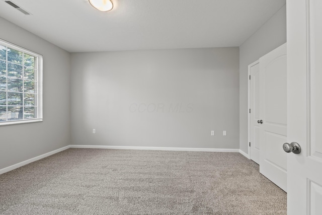 empty room with baseboards, visible vents, and carpet