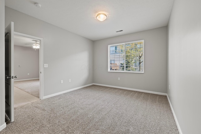 unfurnished room with carpet floors, a ceiling fan, visible vents, and baseboards