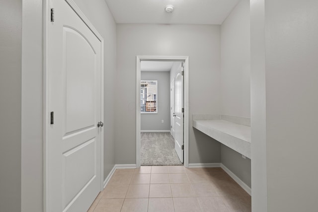 corridor with baseboards and light tile patterned floors