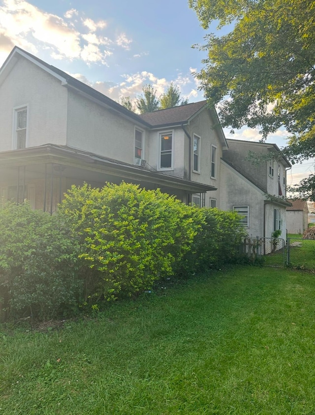 view of home's exterior with a lawn, fence, and stucco siding