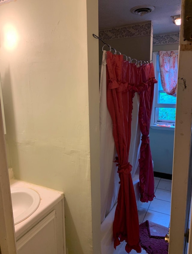 full bathroom with vanity, shower / bath combo with shower curtain, visible vents, and tile patterned floors