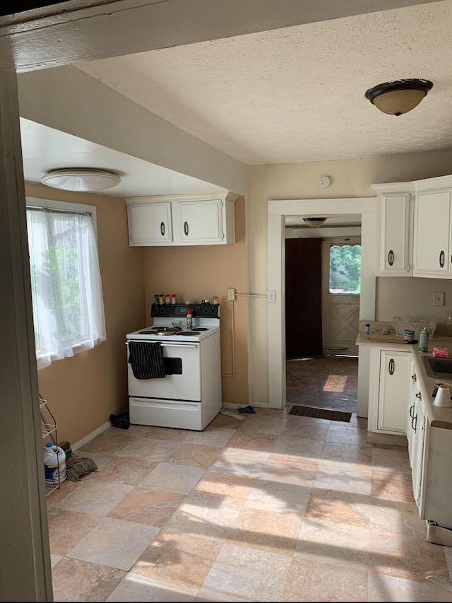 kitchen featuring light countertops, white range with electric stovetop, white cabinets, and baseboards