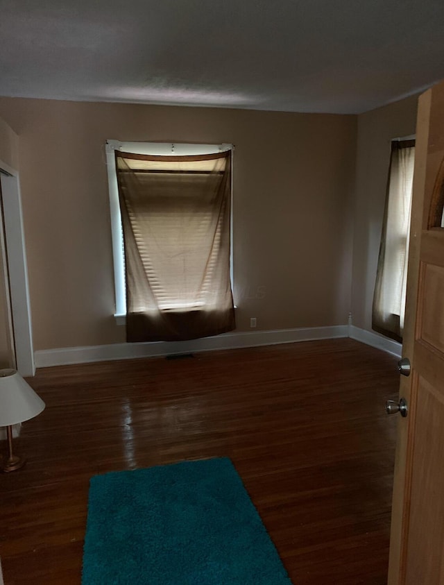 unfurnished room with dark wood-type flooring and baseboards