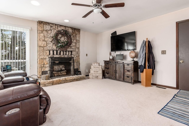 living area with ceiling fan, carpet floors, a stone fireplace, and visible vents