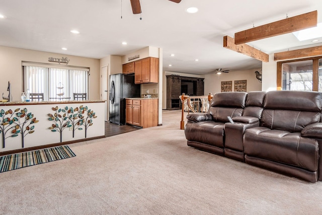 living room with a skylight, ceiling fan, beamed ceiling, dark carpet, and recessed lighting