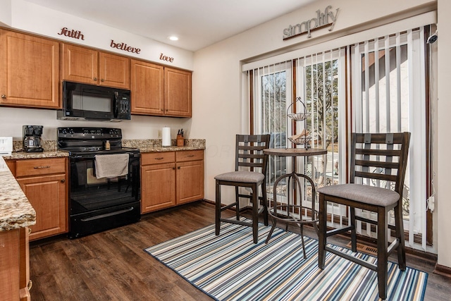 kitchen featuring black appliances, light stone counters, brown cabinetry, and dark wood finished floors