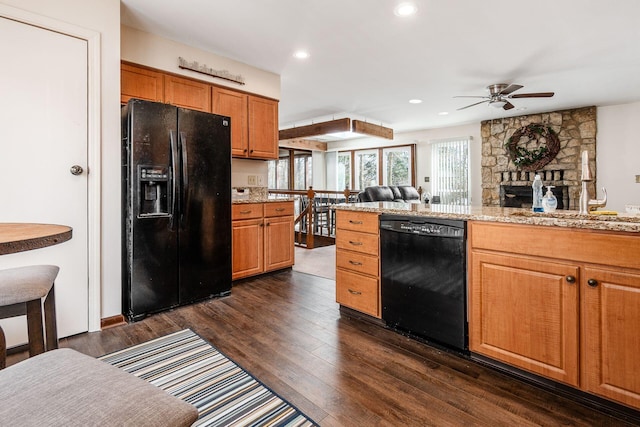 kitchen with dark wood-style floors, light stone counters, brown cabinets, recessed lighting, and black appliances