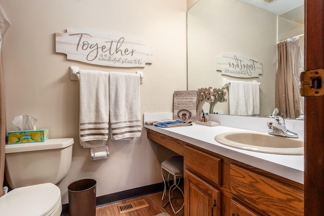 bathroom with toilet, wood finished floors, vanity, visible vents, and baseboards