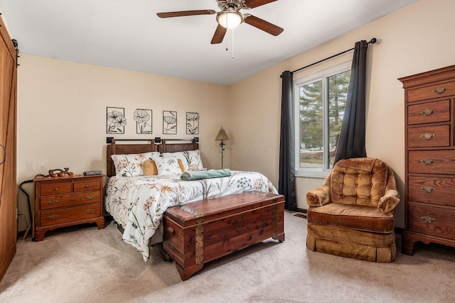 bedroom featuring light carpet, a barn door, and ceiling fan