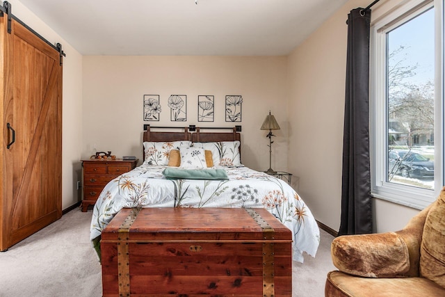 bedroom featuring light carpet, a barn door, multiple windows, and baseboards