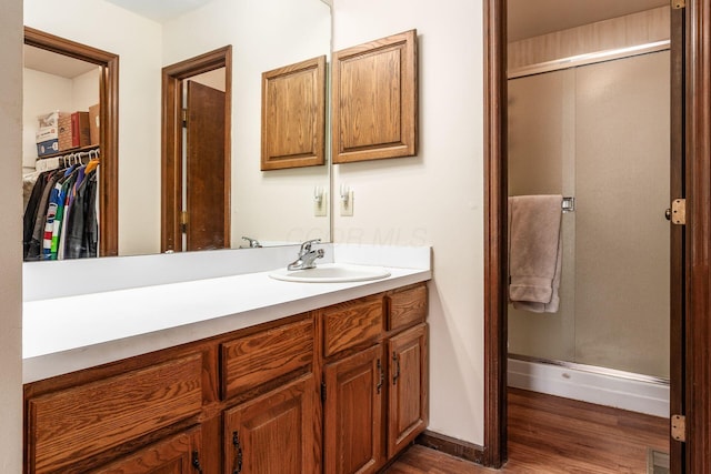 full bath with wood finished floors, visible vents, vanity, a spacious closet, and a shower stall