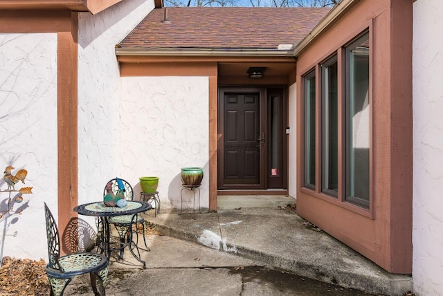 doorway to property with a shingled roof and stucco siding