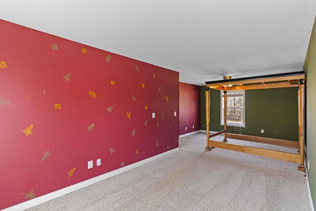 empty room featuring a textured ceiling, carpet floors, and baseboards