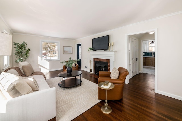 living area featuring crown molding, dark wood-style flooring, a brick fireplace, and baseboards