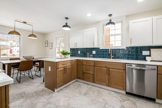 kitchen with hanging light fixtures, stainless steel dishwasher, light countertops, and white cabinetry